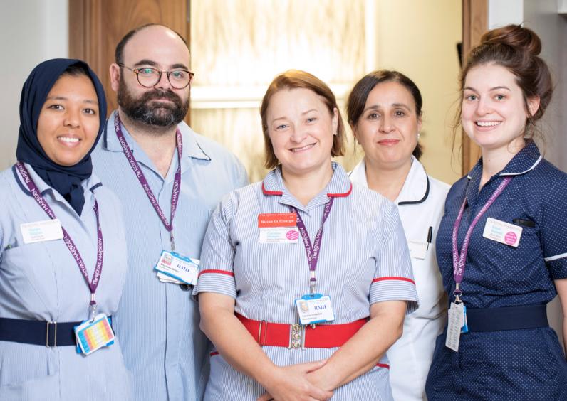 Nargis Begum, Senior Staff Nurse in blue striped uniform with red piping, wearing headscarf, Marcelino Molina, Staff Nurse in striped uniform, wearing glasses, Caroline Stanger, Senior Staff Nurse in blue striped uniform with red piping, Neli HCA in white uniform and Sarah Barwell, Ward Sister in navy spotted uniform in Granard House.