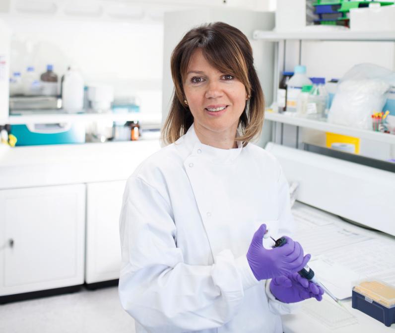 Dr Samra Turajlic, Consultant Medical Oncologist at The Royal Marsden, stands in her lab wearing a white coat and purple gloves